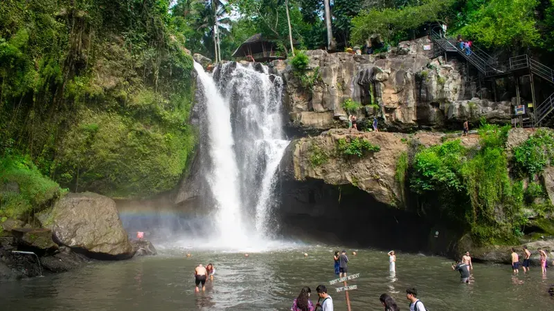 Visitors swimming in the wide pool below Tegenungan Waterfall near Ubud Bali on a Bali waterfall tour